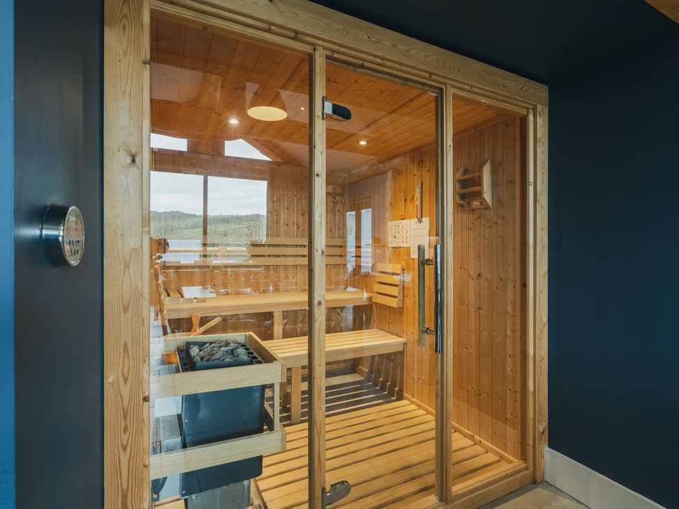 A sauna with a glass door and wooden benches at The Farmhouse in Addingham