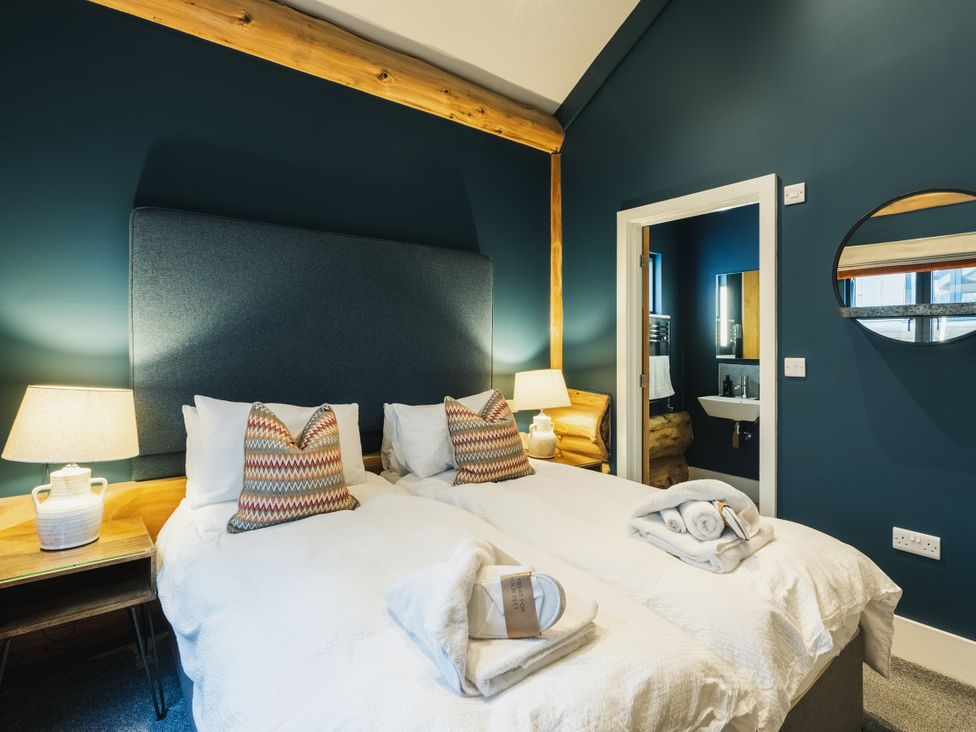A bedroom with twin beds and a bathroom visible at The Farmhouse in Addingham