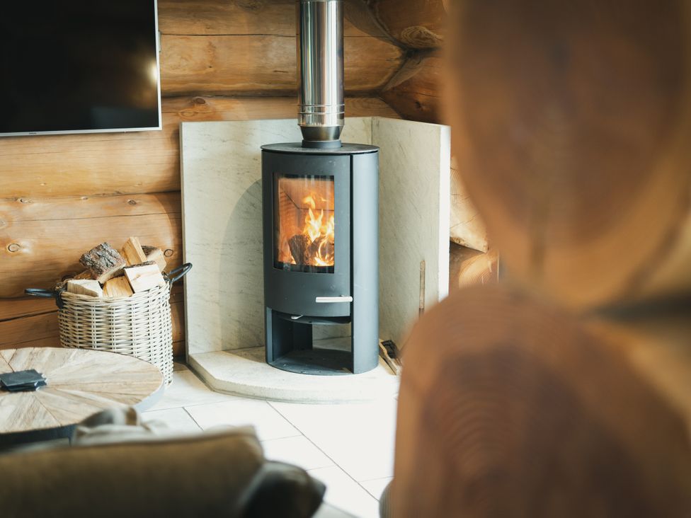 A living room with a fireplace and a wood basket at Apres Ski in Addingham