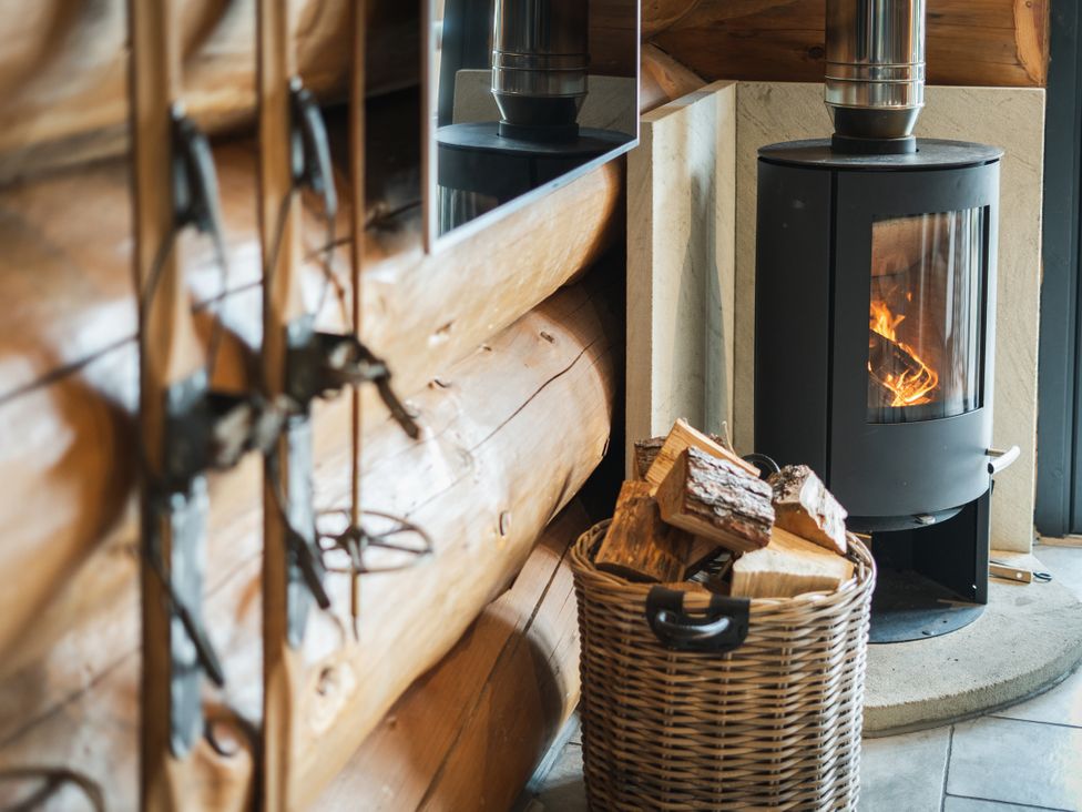 A living room with a fireplace and wood basket at Apres Ski in Addingham