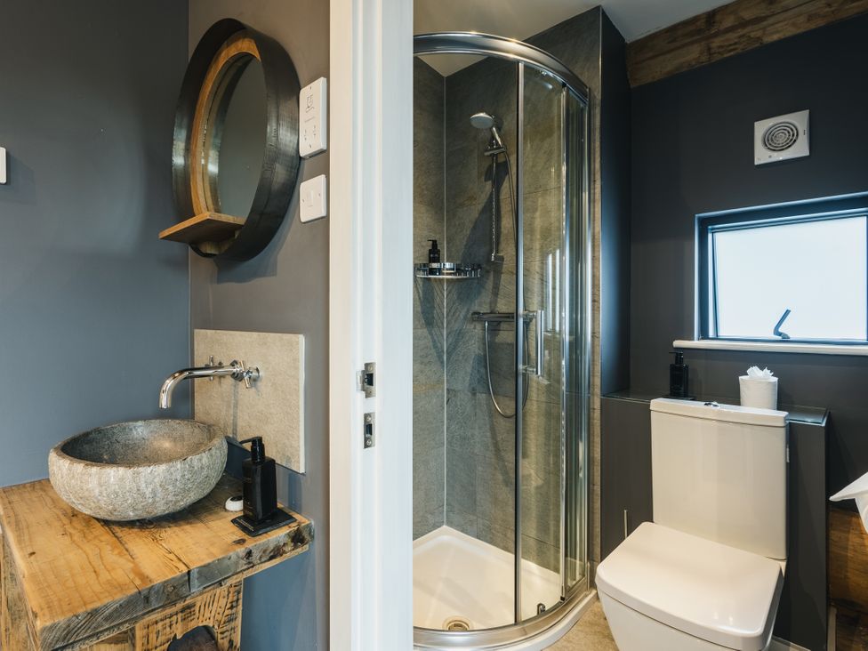 A bathroom with a sink, toilet, shower, and mirror at Apres Ski in Addingham