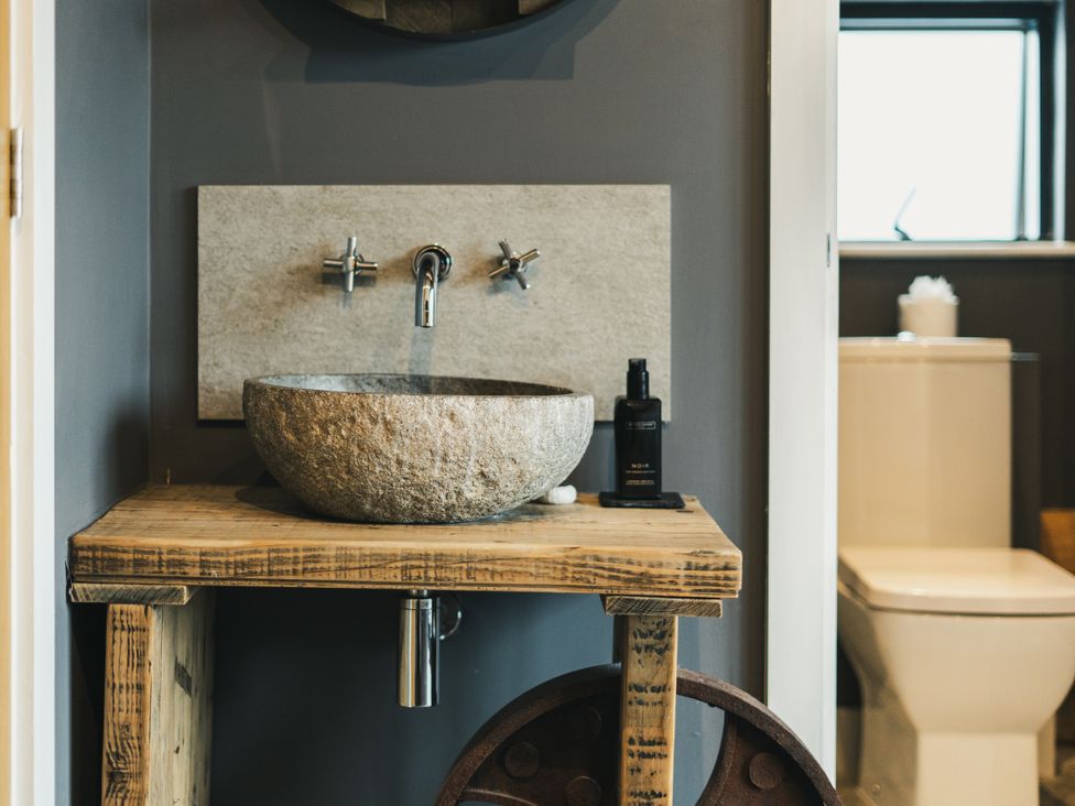 A bathroom with a stone sink and wooden shelf at Apres Ski in Addingham