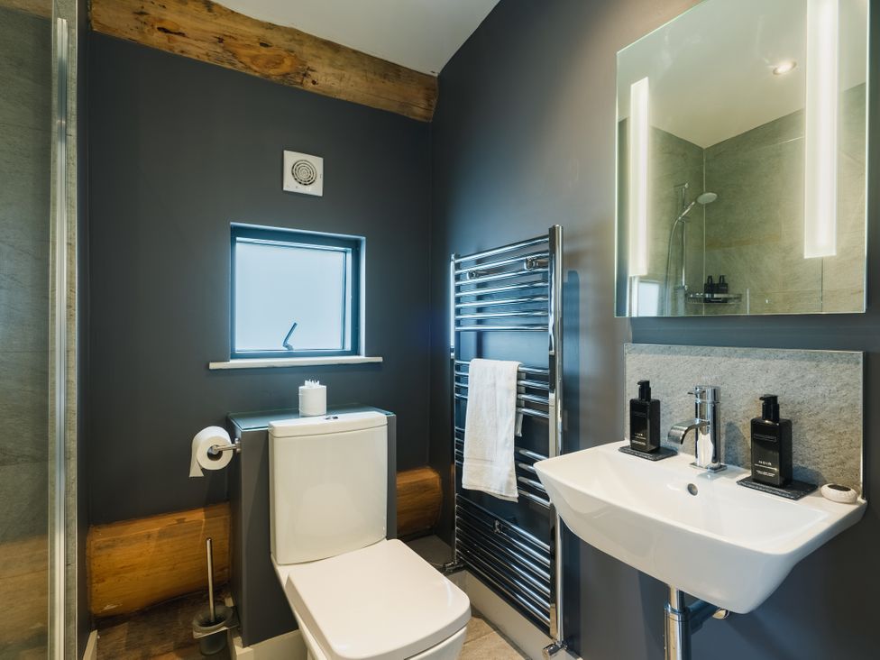 A bathroom with a toilet, sink, and mirror at Apres Ski in Addingham