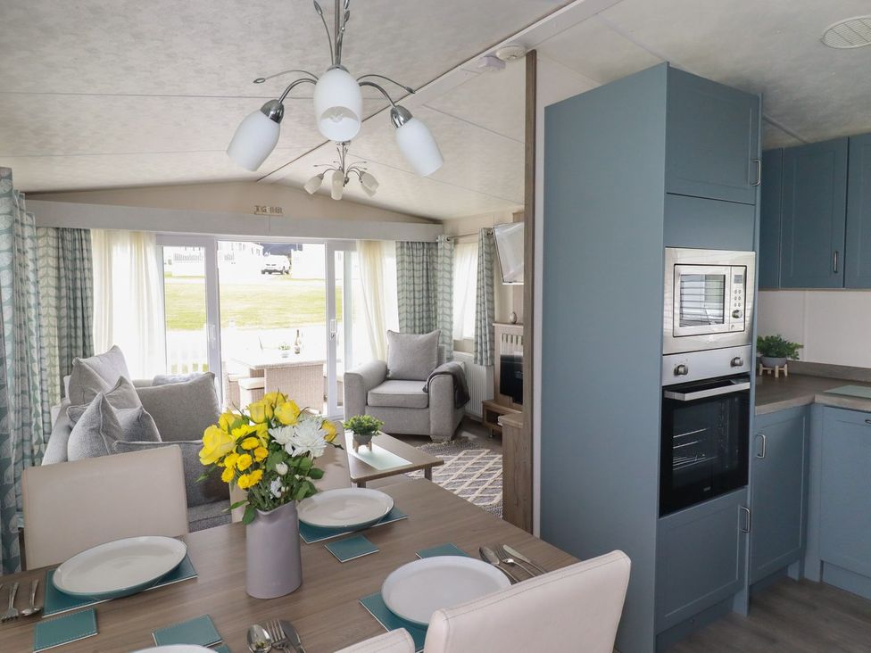 A living room with a dining area and kitchen appliances at No. 4 Fistral in Newquay