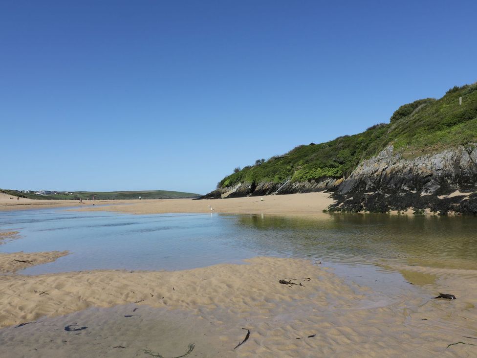 A beach scene with water and hills at No. 4 Fistral in Newquay