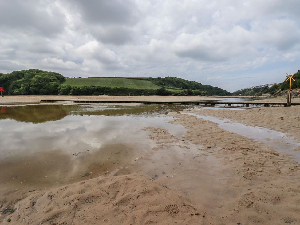 A beach with water and a wooden pier at No. 4 Fistral in Newquay