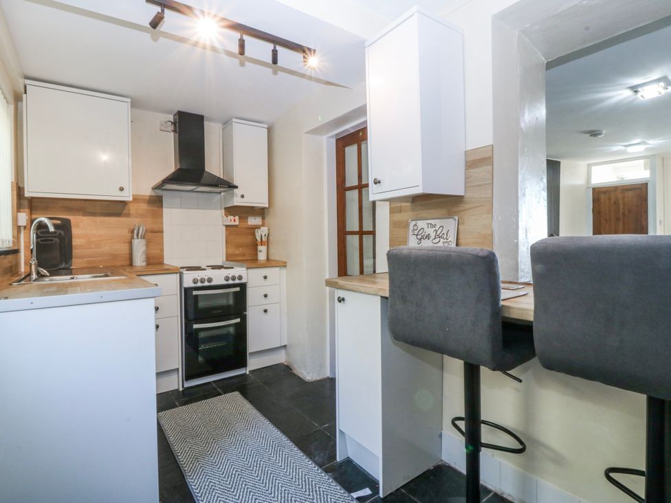 A kitchen with cabinets and bar stools at Tegfan in Garndolbenmaen near Porthmadog