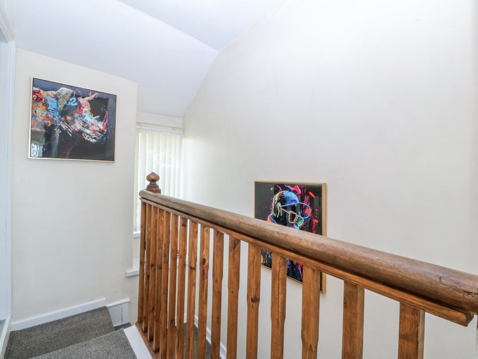 A hallway with a staircase and artworks on the wall at Tegfan in Garndolbenmaen near Porthmadog
