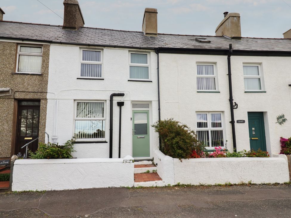 A terraced house with a front door and flower bed at Tegfan in Garndolbenmaen