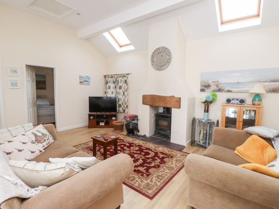 A living room with a fireplace and television at Swallow Cottage in Llangefni