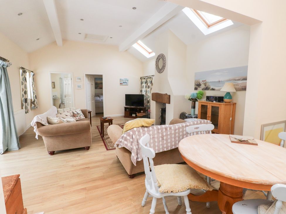 A living room with a sofa and dining table at Swallow Cottage in Llangefni