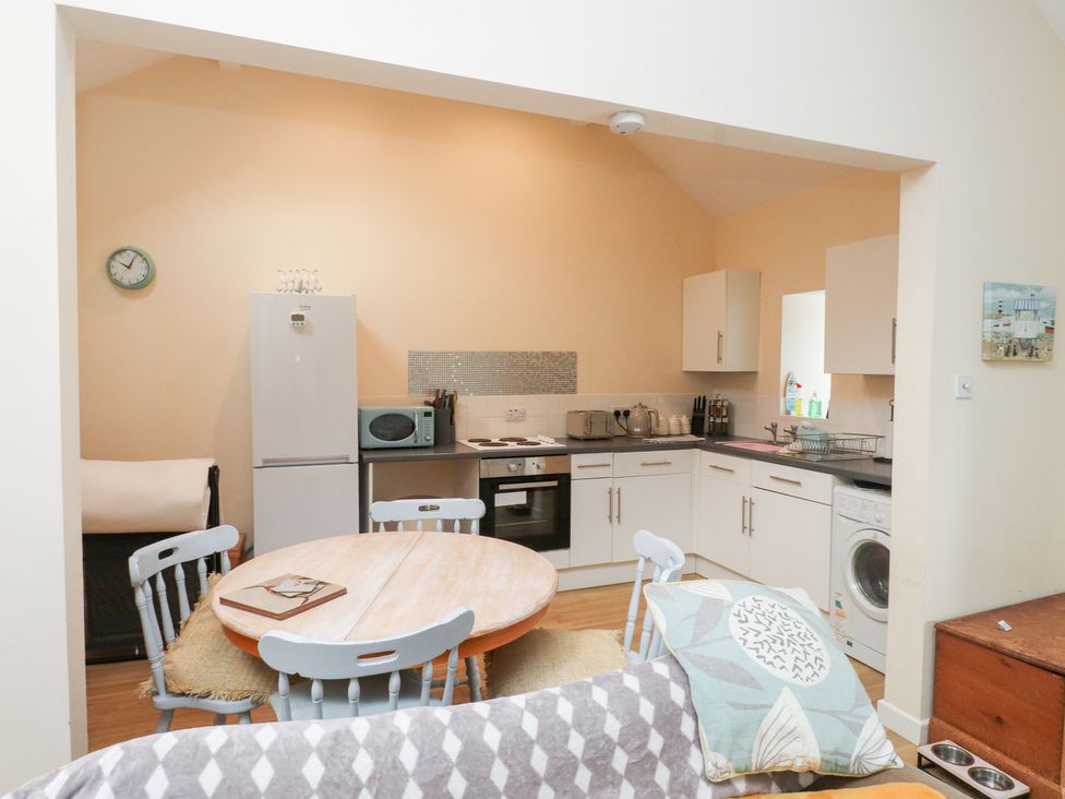 A kitchen with appliances and dining area at Swallow Cottage in Llangefni