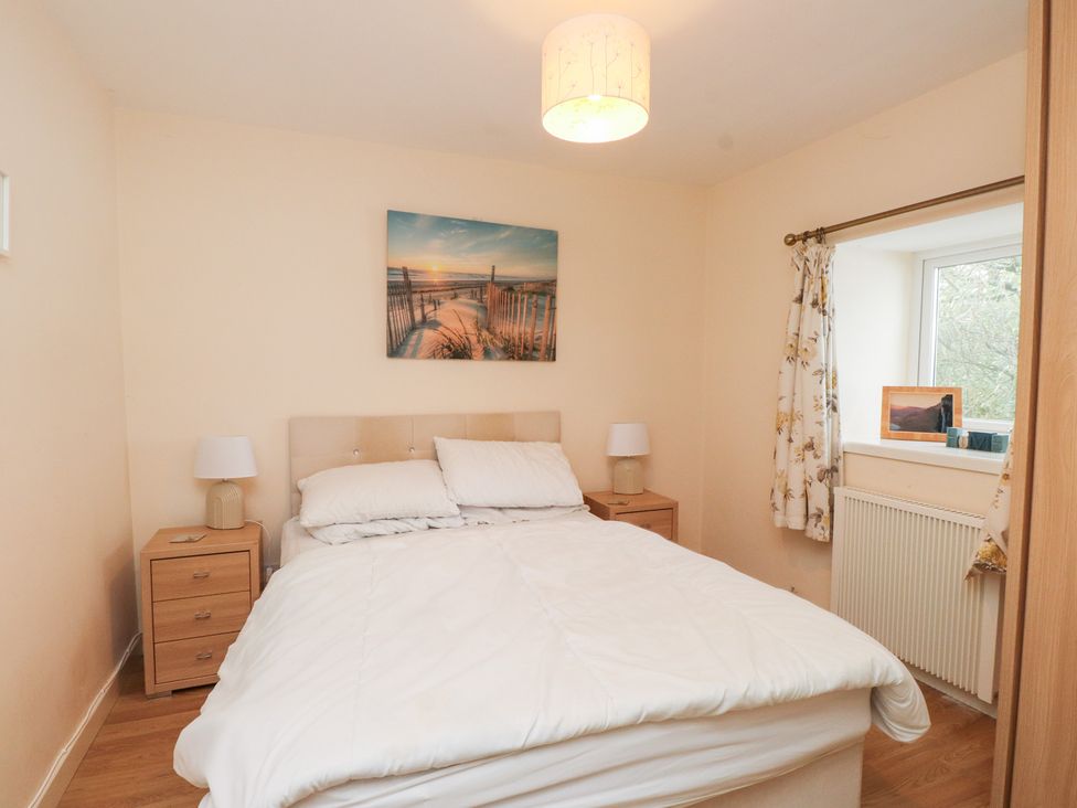A bedroom with a bed and nightstand at Swallow Cottage in Llangefni