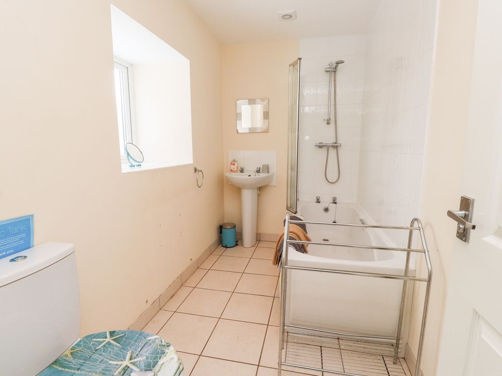 A bathroom with a bathtub, sink, and toilet at Swallow Cottage in Llangefni