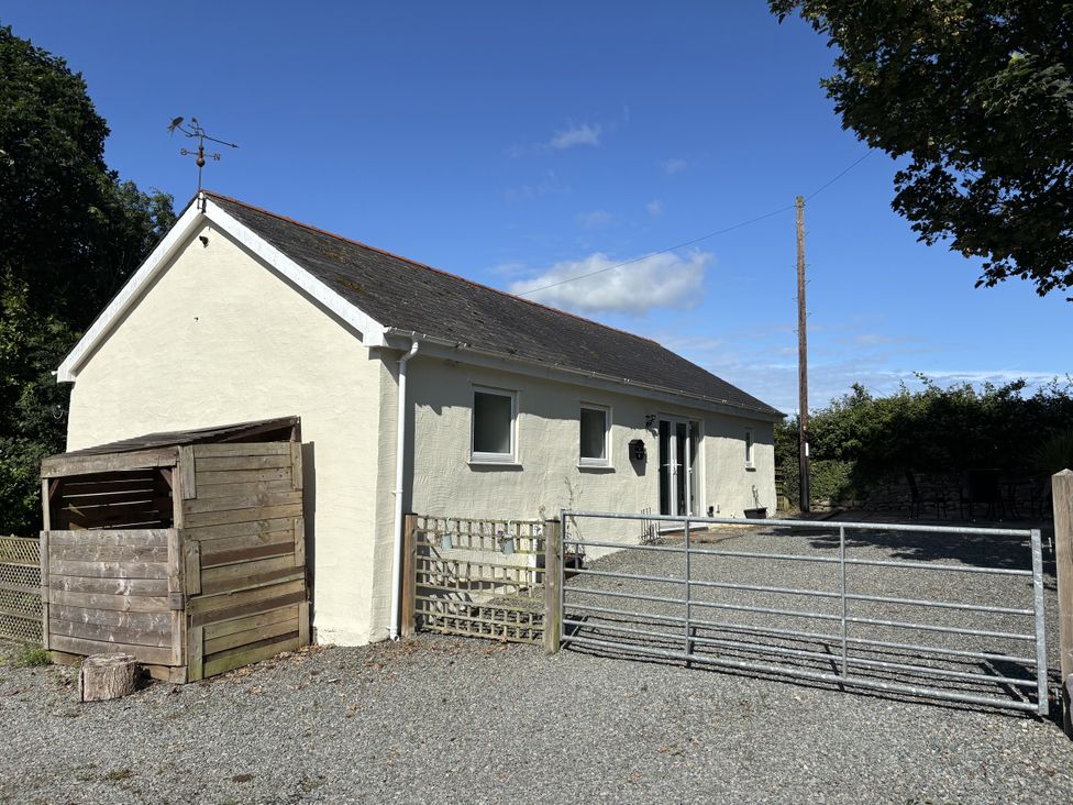 A house with a gravel driveway and a gate at Swallow Cottage in Llangefni