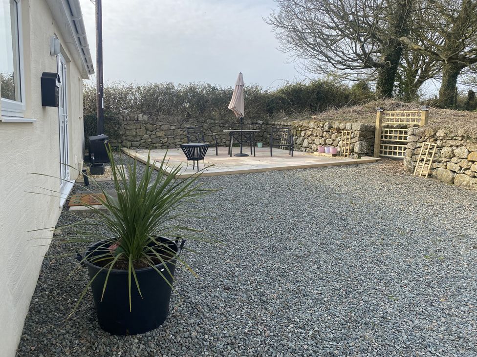 A garden with a patio and seating area at Swallow Cottage in Llangefni