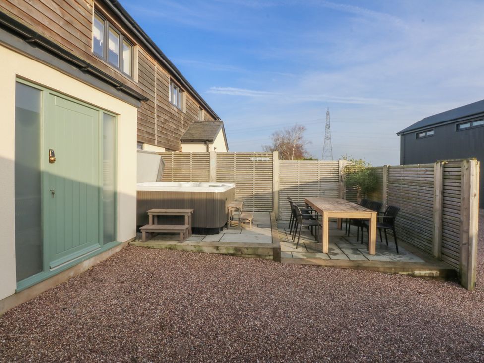 A garden with a hot tub and dining table at Bell House in Llanfechell
