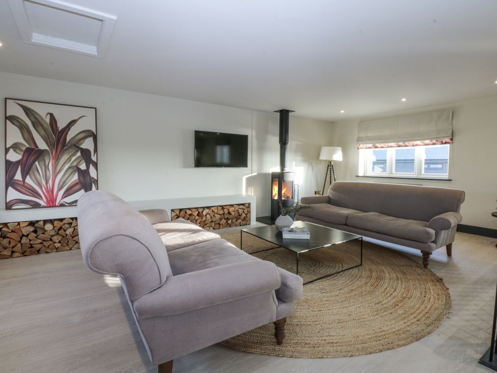 A living room with sofas and a fireplace at Bell House in Llanfechell