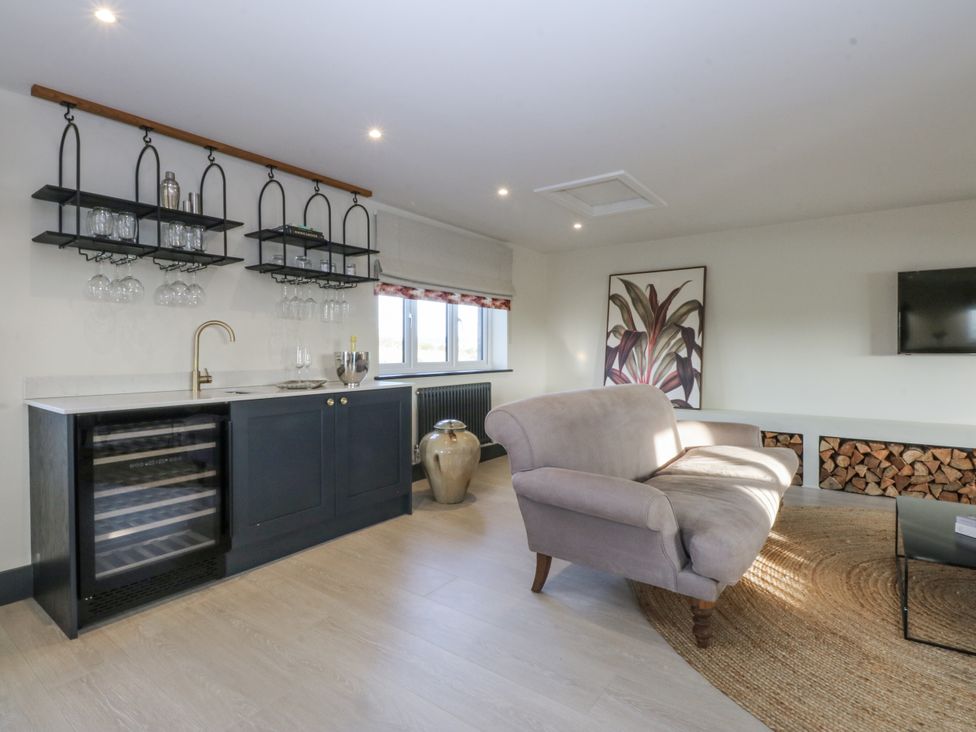 A snug with a bar area, sofa and television at Bell House in Llanfechell