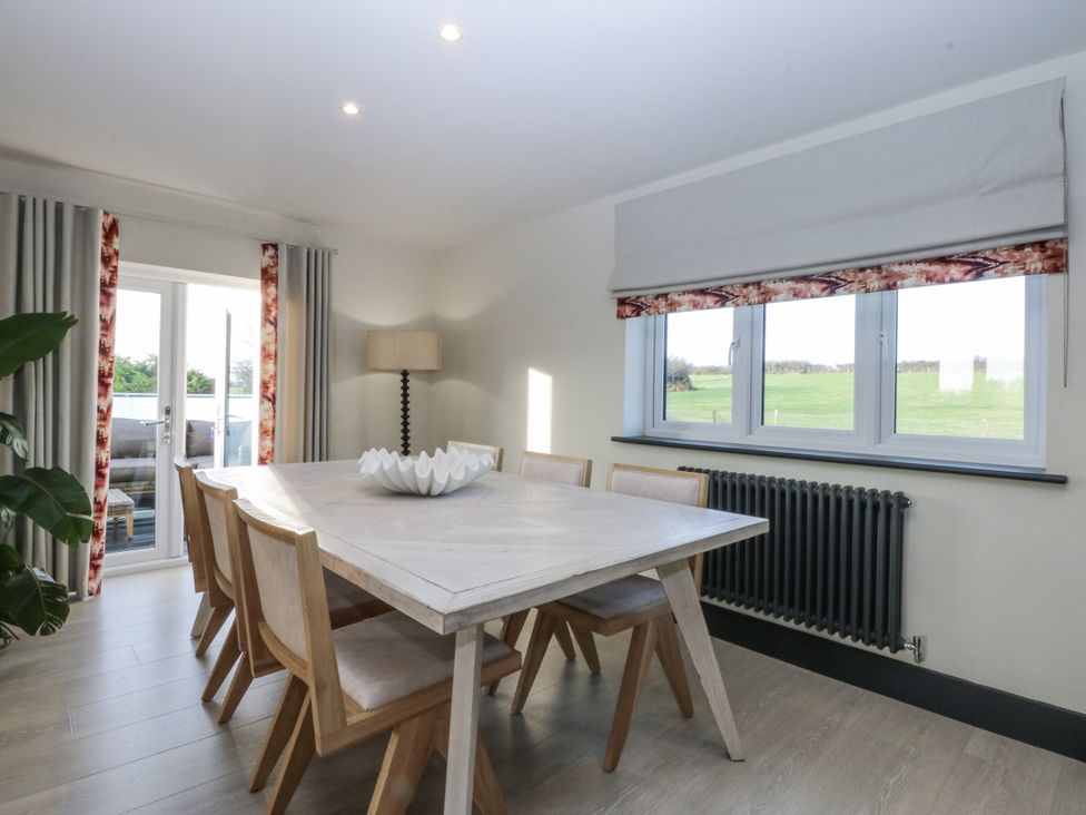 A dining room with a table and chairs at Bell House in Llanfechell