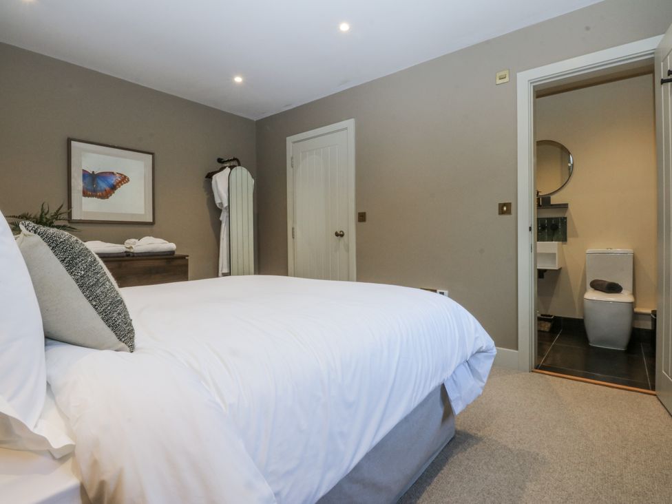 A bedroom with a bed and ensuite bathroom at Bell House Llanfechell