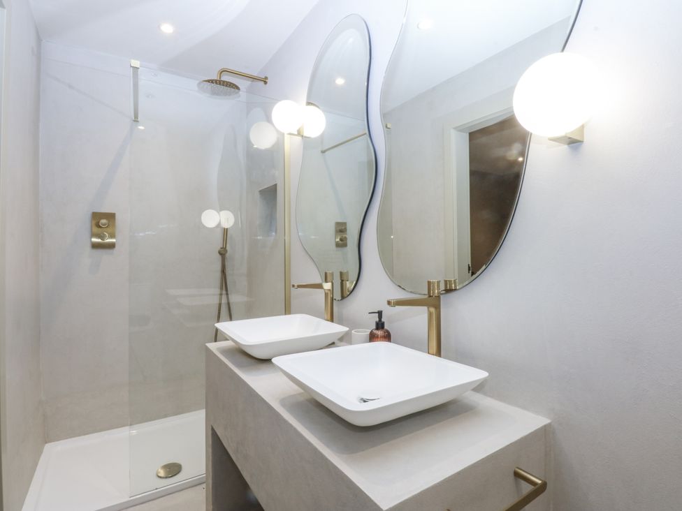 A bathroom with a shower and dual sinks at Bell House in Llanfechell