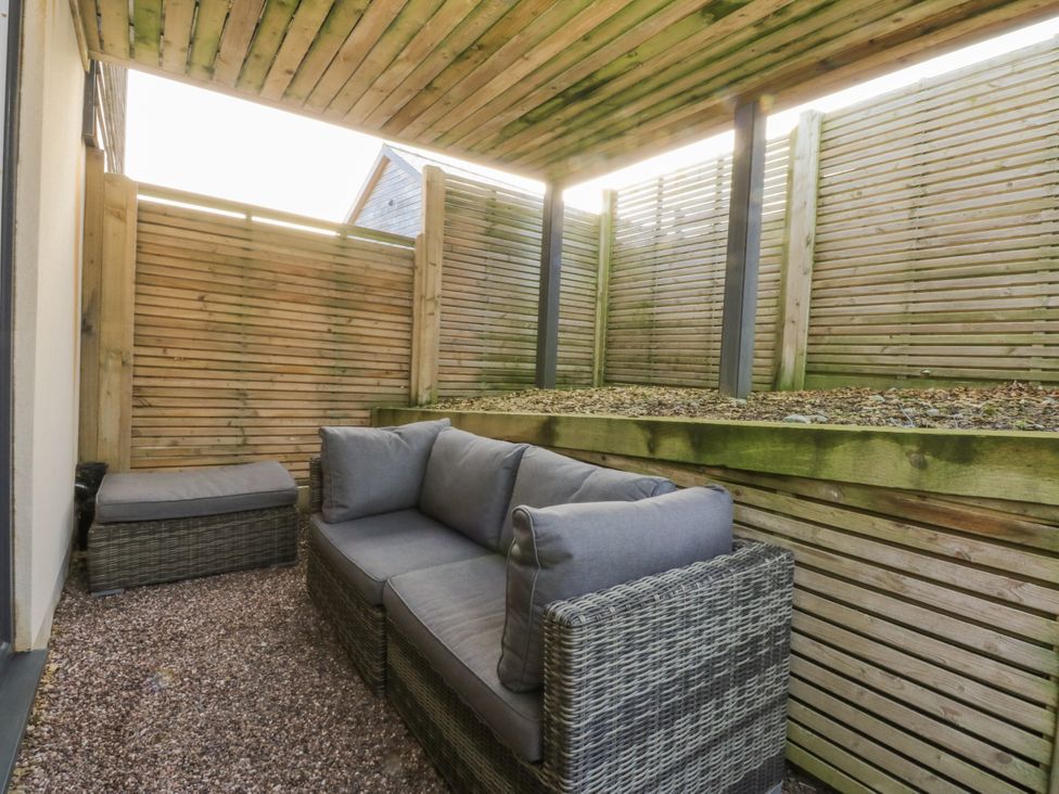 A seating area with a sofa and fence at Bell House in Llanfechell