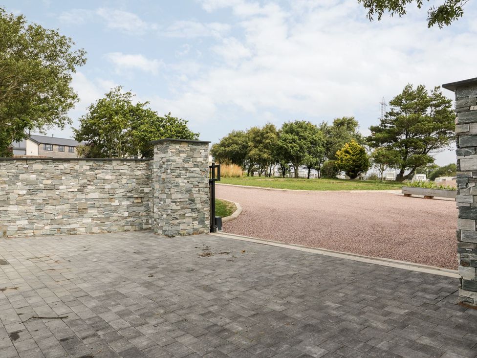 A stone wall with a gate and gravel path at Bell House in Llanfechell