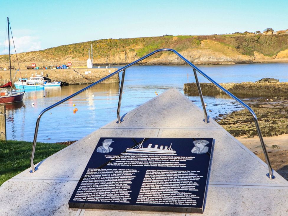 A view of a harbor with boats and a plaque at Bell House in Llanfechell