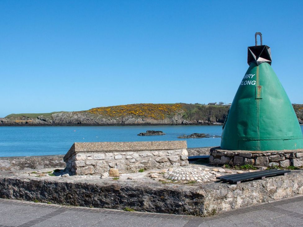 A coastal view with a buoy and rocky shoreline at Bell House Llanfechell