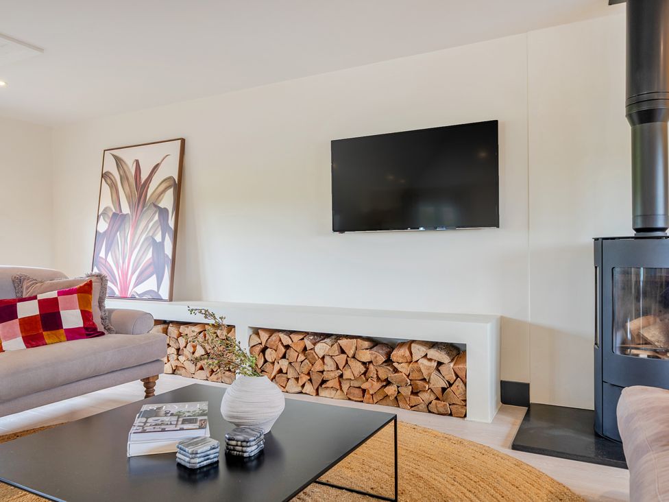 A living room with a television and a fireplace at Bell House in Llanfechell