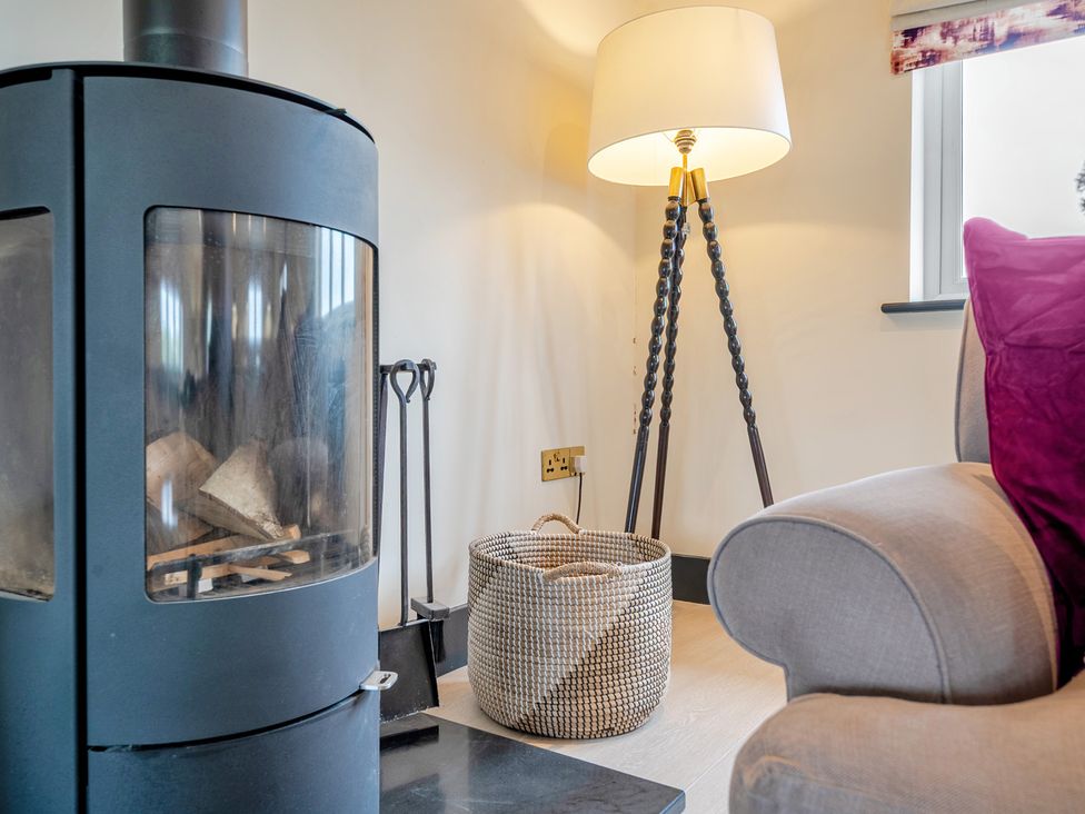 A living room with a fireplace and lamp at Bell House in Llanfechell