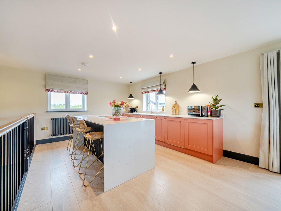 A kitchen with an island and stools at Bell House in Llanfechell