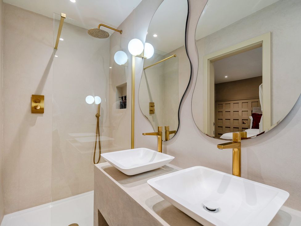 A bathroom with shower, sinks and mirrors at Bell House in Llanfechell