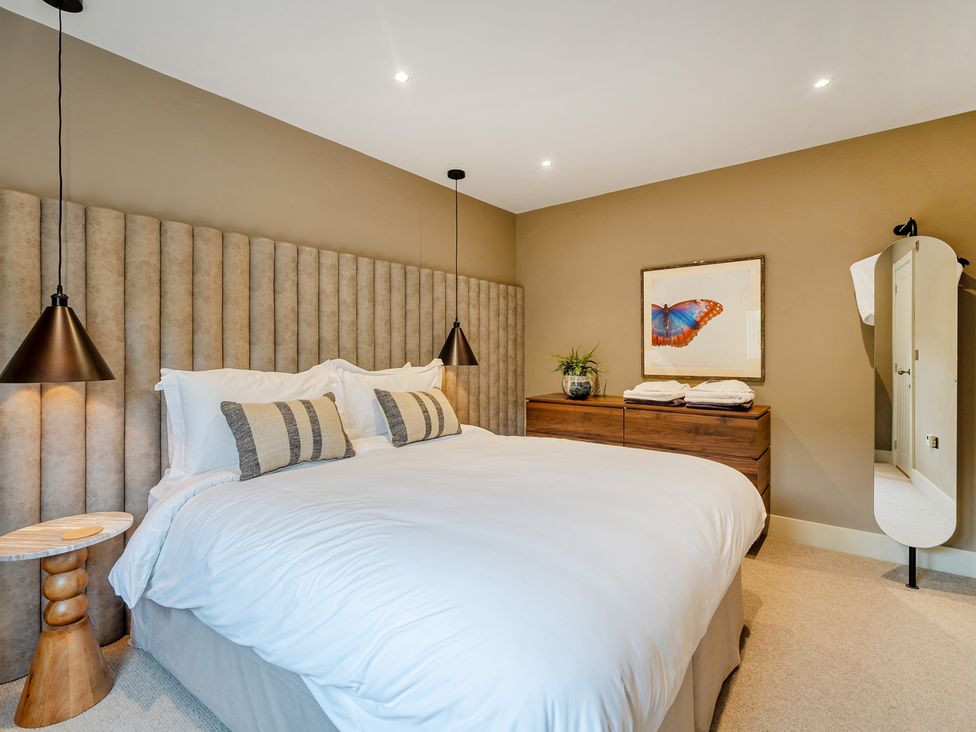 A bedroom with a bed, bedside table, and dresser at Bell House Llanfechell