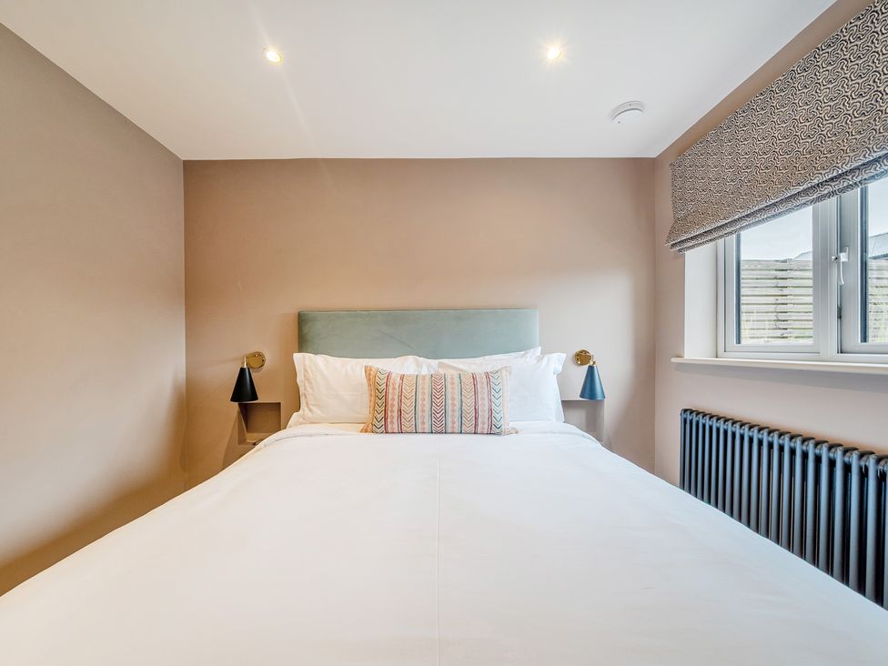 A bedroom with a bed and wall lamp at Bell House in Llanfechell