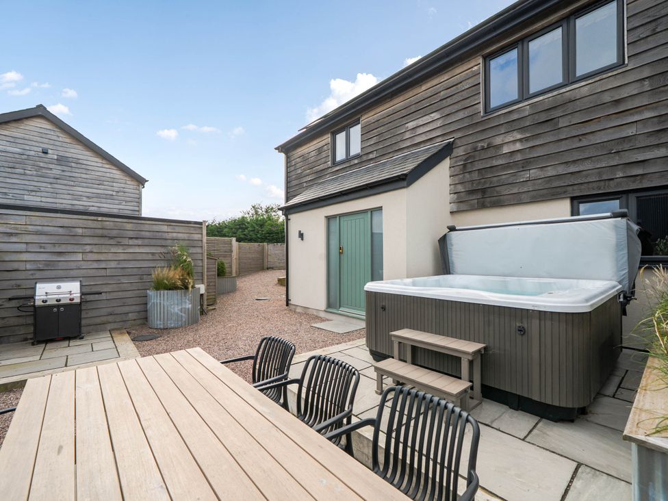 An outdoor area with a hot tub and dining set at Bell House in Llanfechell