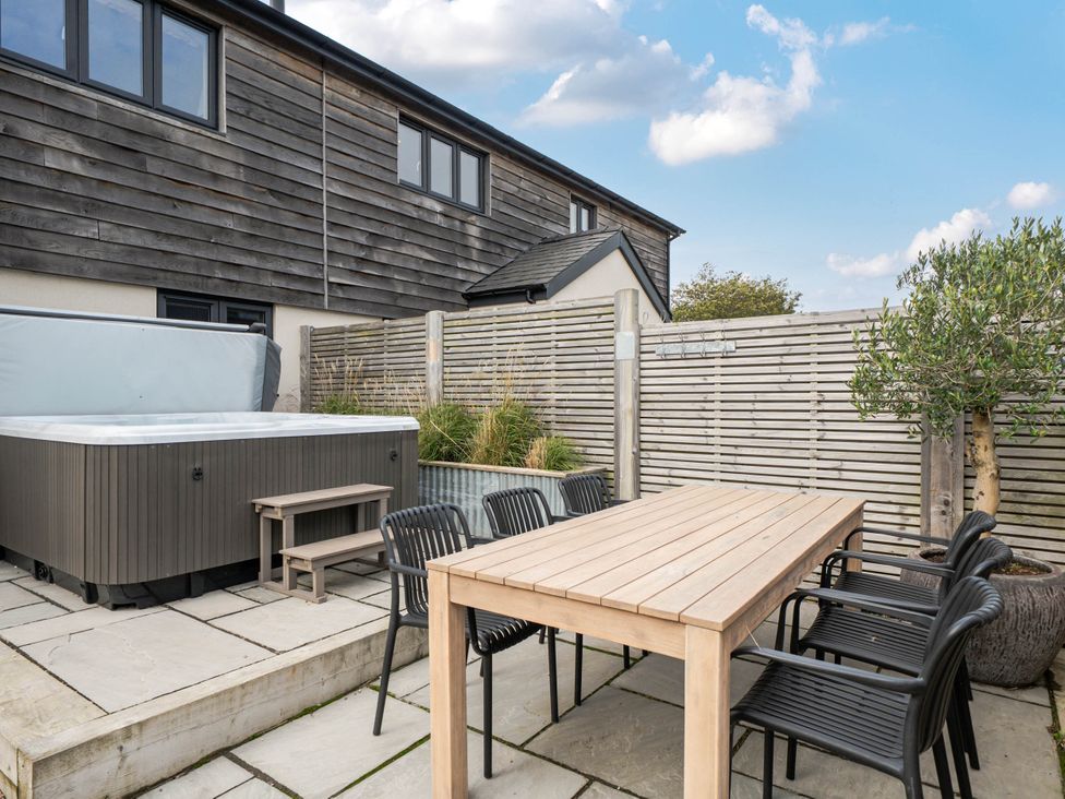 An outdoor area with a hot tub and dining table at Bell House in Llanfechell