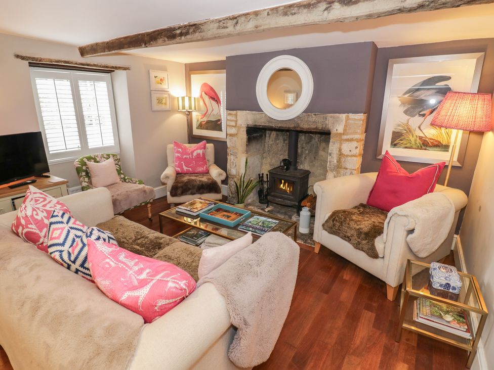A living room with armchair and fireplace at 23 New Church Street Tetbury