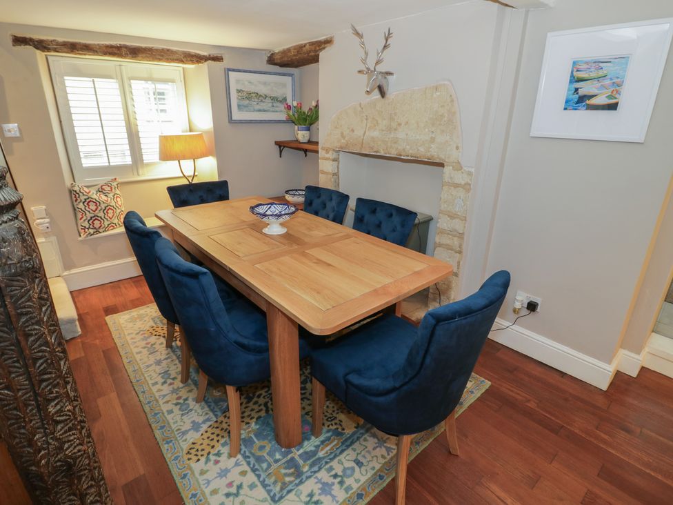 A dining room with a wooden table and blue chairs at 23 New Church Street Tetbury