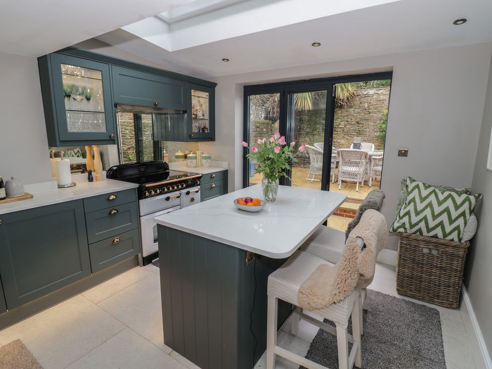 A kitchen with a stove and dining table at 23 New Church Street Tetbury