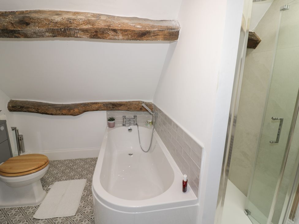A bathroom featuring a bathtub, toilet, and shower at 23 New Church Street Tetbury