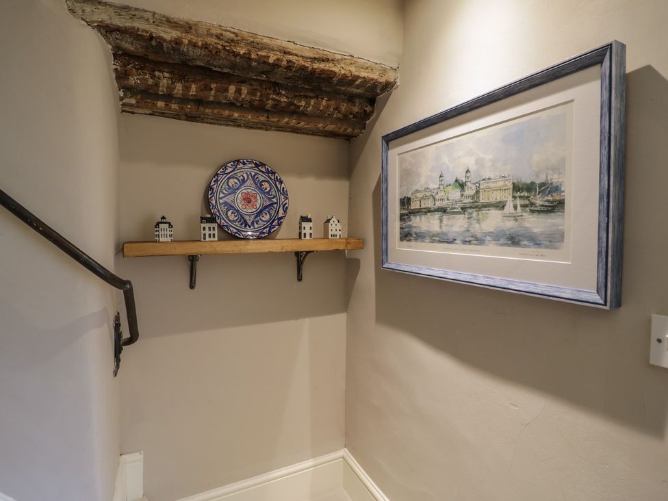 A staircase with a shelf, decorative plate, and framed painting at 23 New Church Street in Tetbury