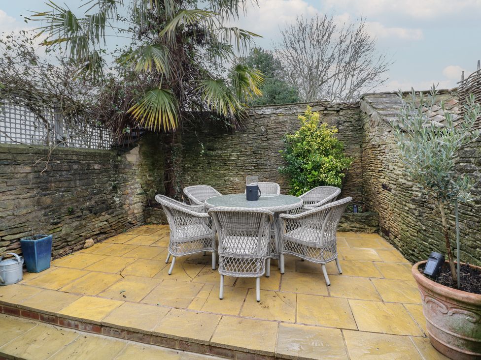 A garden with a table and chairs surrounded by stone walls at 23 New Church Street Tetbury