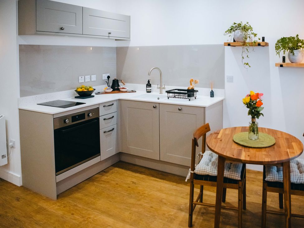 A kitchen with cabinets and a dining table at Ammil Bespoke