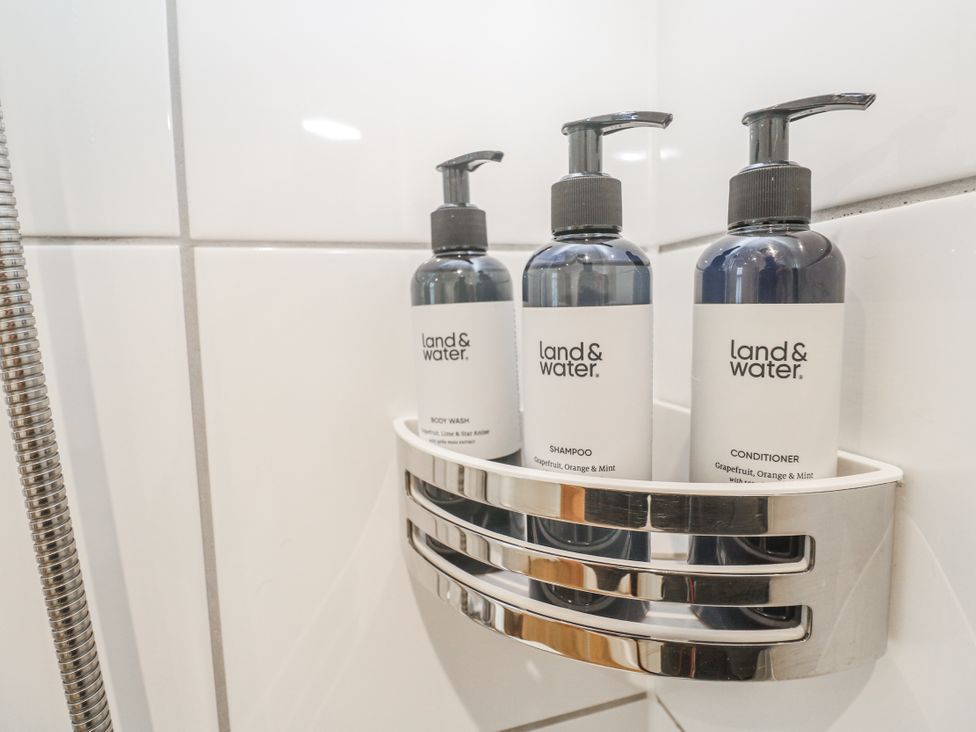 A shower dispenser holding shampoo, conditioner, and body wash at Ammil Bespoke in St Ives