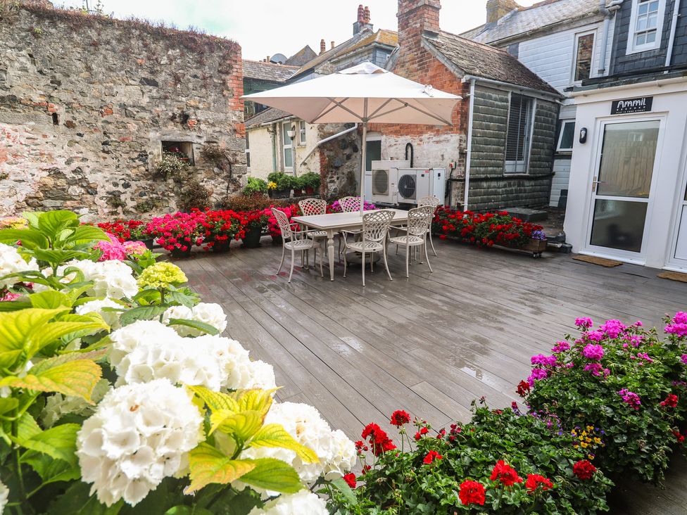 An outdoor area with a table and chairs shaded by an umbrella at Ammil Bespoke in St Ives