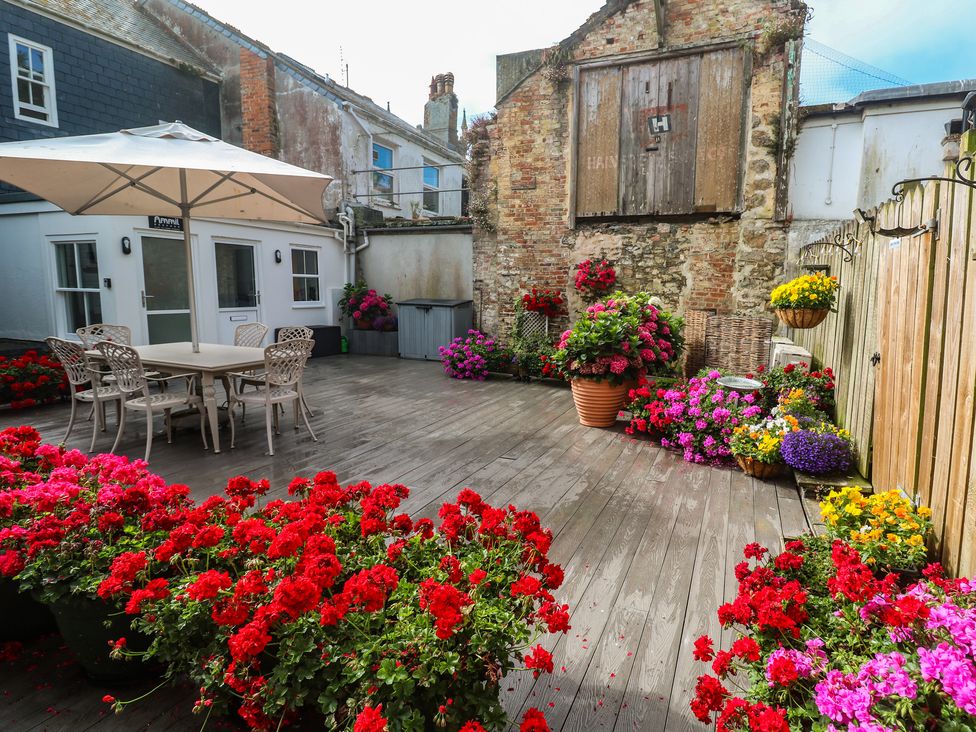 A garden with a table and chairs surrounded by flowers at Ammil Bespoke in St Ives