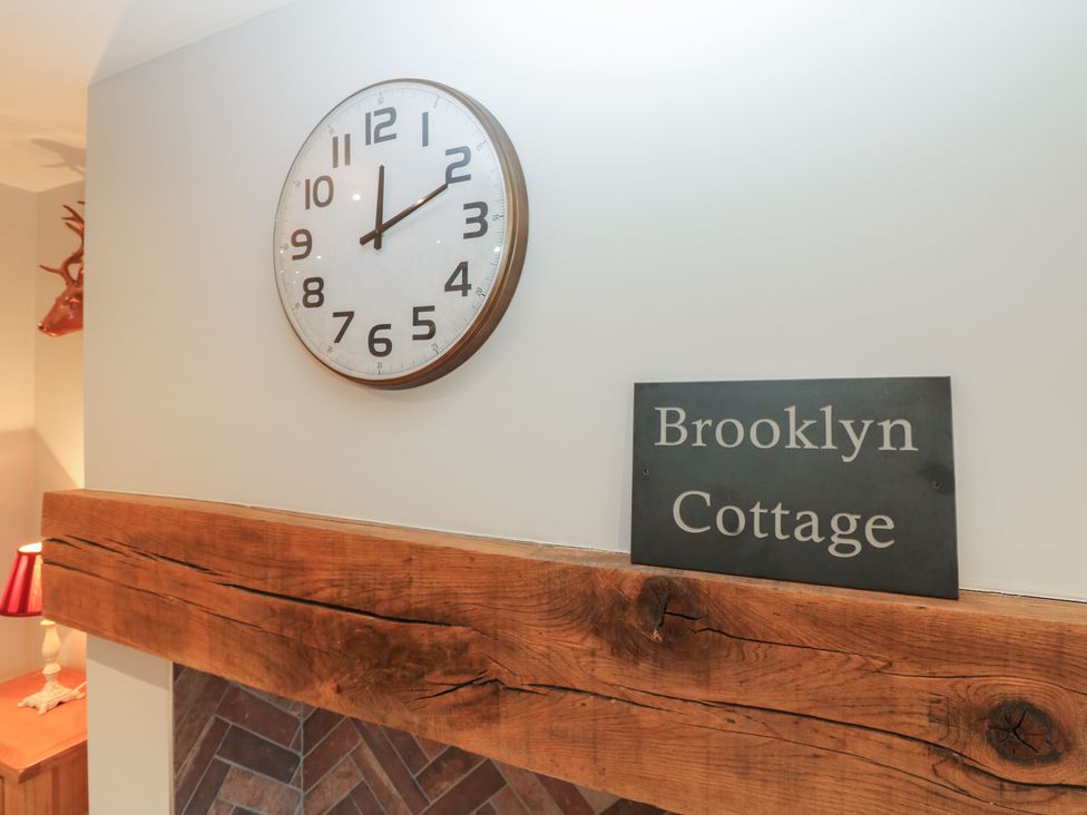 A clock and sign on wooden mantel at Brooklyn Cottage in Kirkby Malzeard