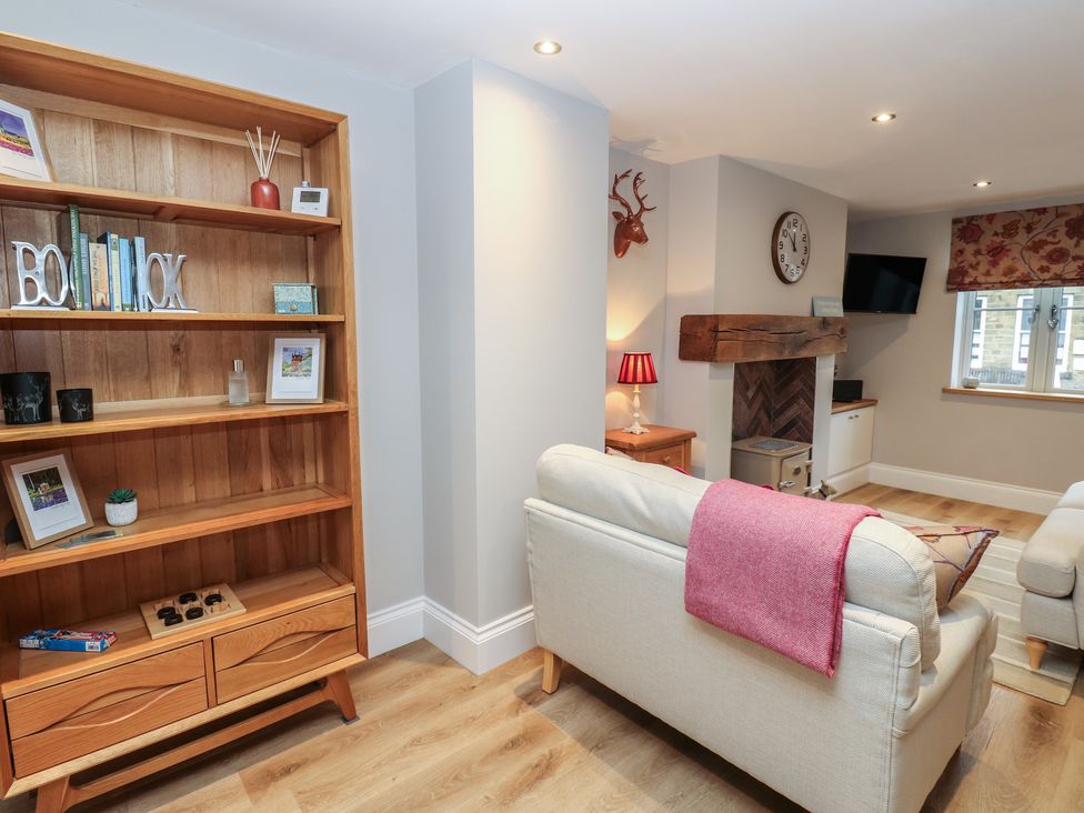 A living room with a bookshelf and sofa at Brooklyn Cottage in Kirkby Malzeard